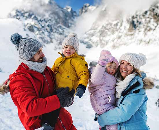 Father and mother with two small children in winter nature, standing in the snow.